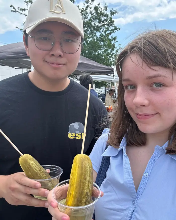 Chris and friend pose for a photo holding pickles they purchased at the famer's market