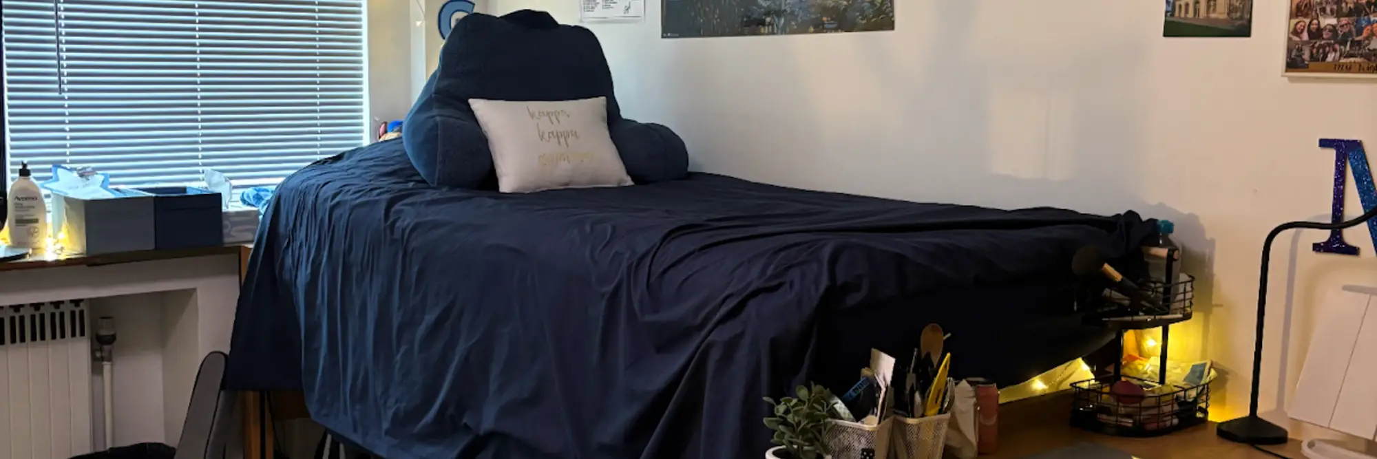 An image of Miriam's dorm room, showing her desk and bed with decorations on the wall.