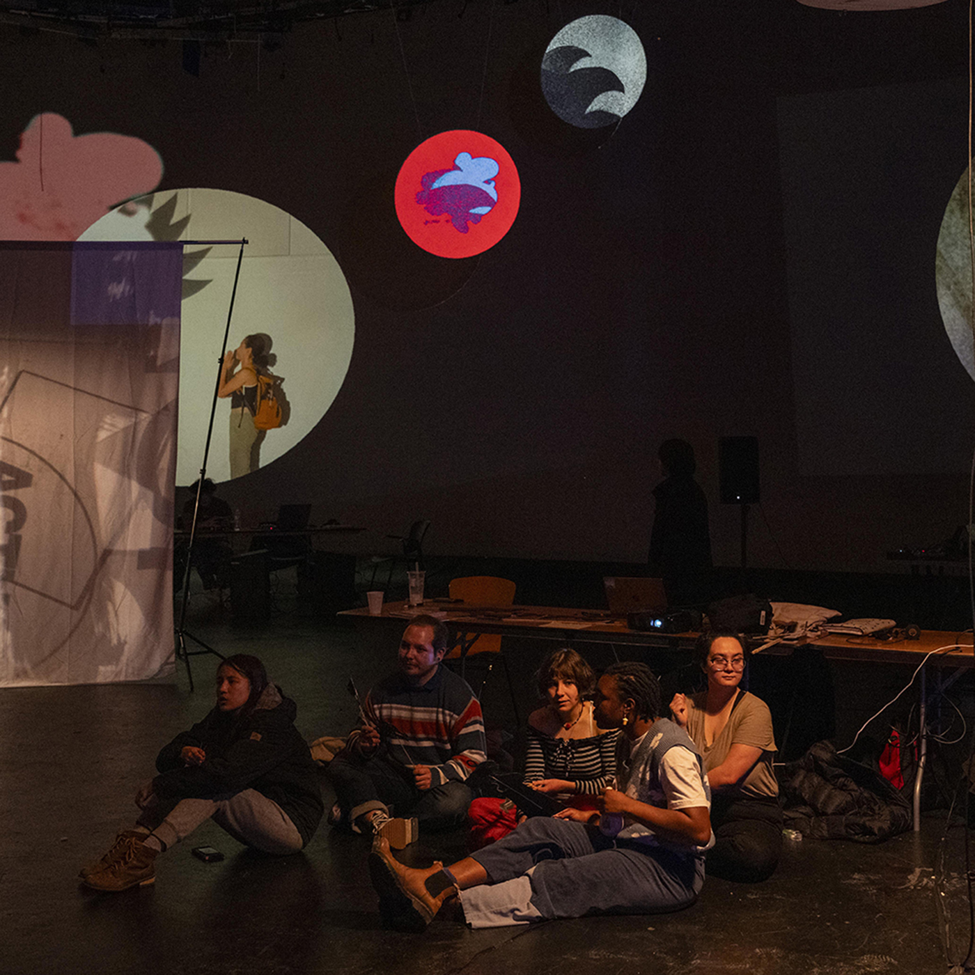 students seated on floor looking at projections on wall